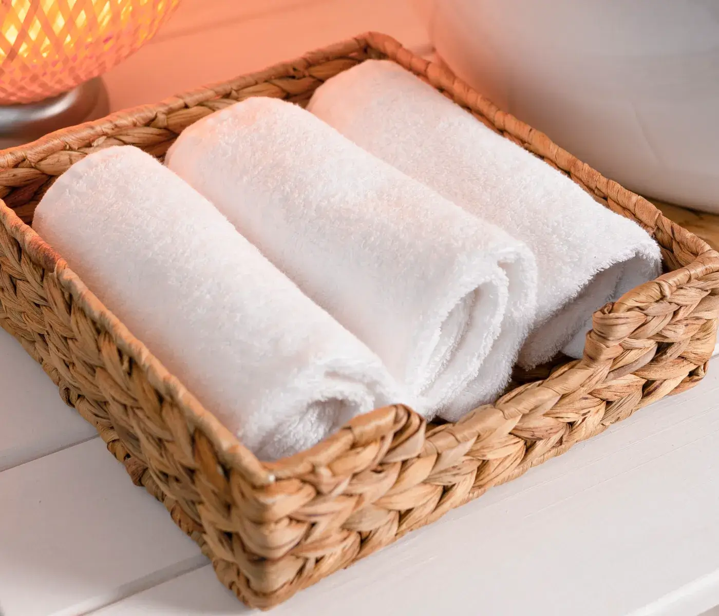 a wicker basket with three white towels in it