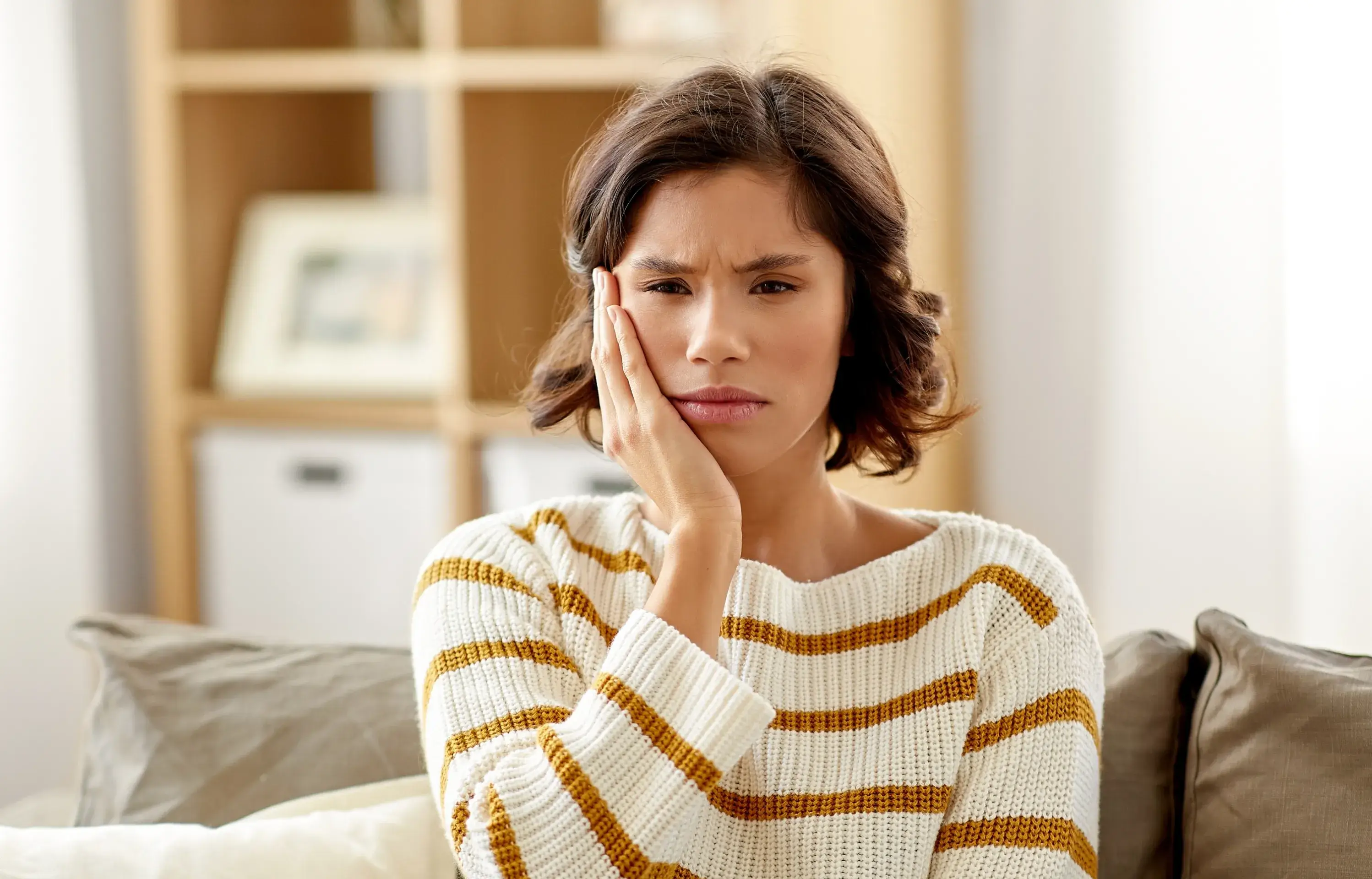 a woman sitting on a couch holding her hand to her face