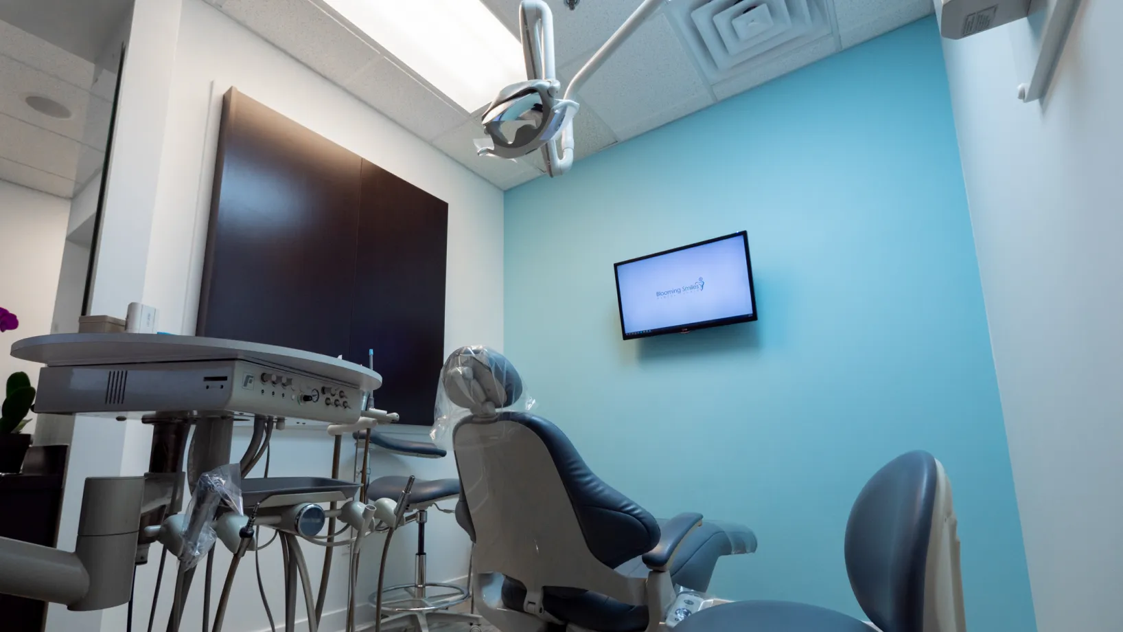 a dental room with a monitor and chairs